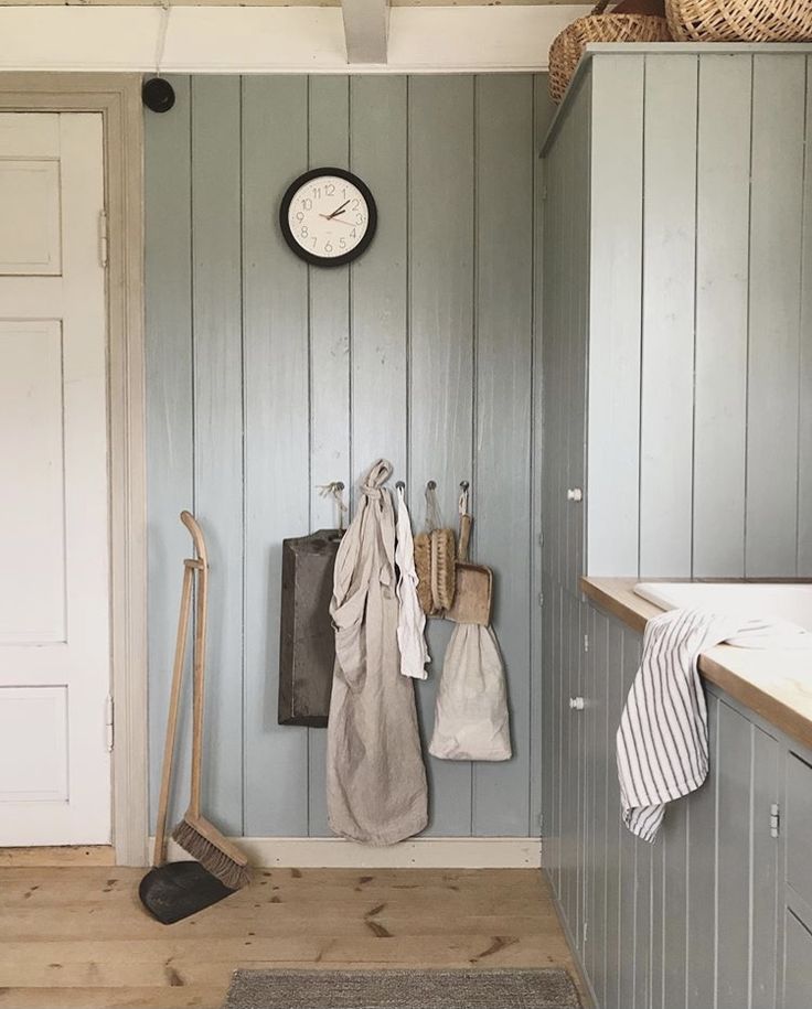 there is a clock hanging on the wall next to some towels and brooms in this room