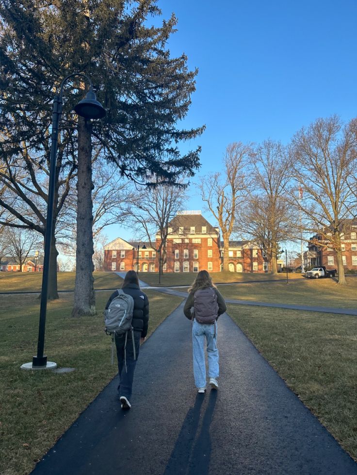 two people walking down a path in the park