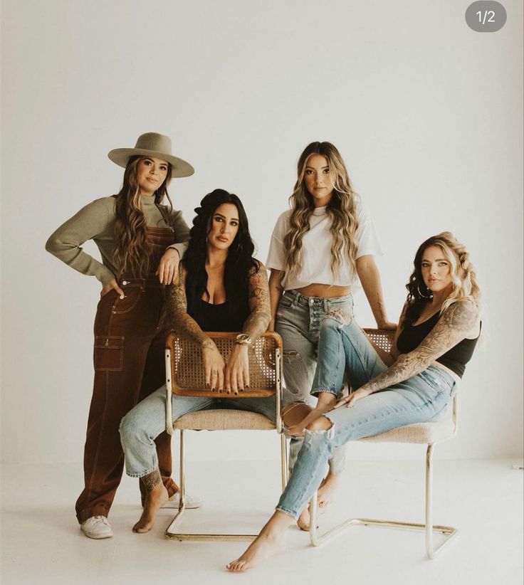 four women are sitting on a chair posing for a photo in front of a white background