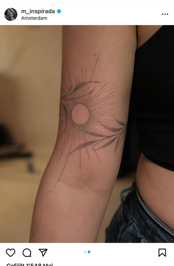 a woman's arm with a sun tattoo on the left side of her arm