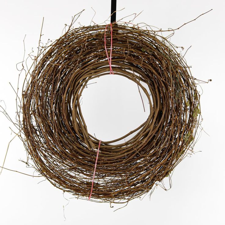 a close up of a wreath on a white background with red string hanging from it