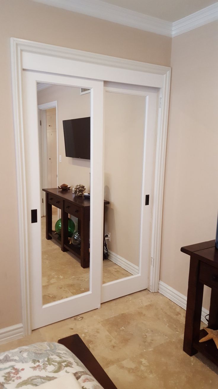 an empty room with two doors and a television mounted on the wall in it's corner