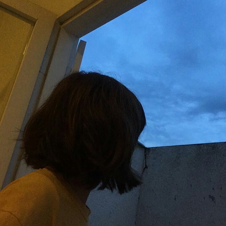 a person standing in front of a window looking out at the sky