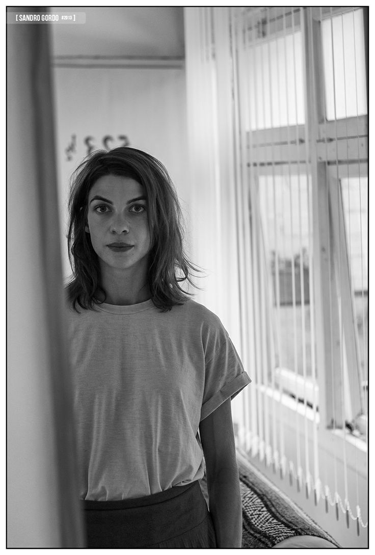 a black and white photo of a woman standing in front of a window