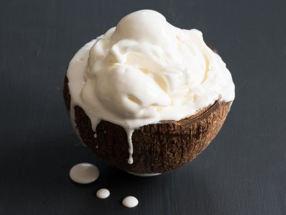 a cupcake with white icing and sprinkles on a black surface