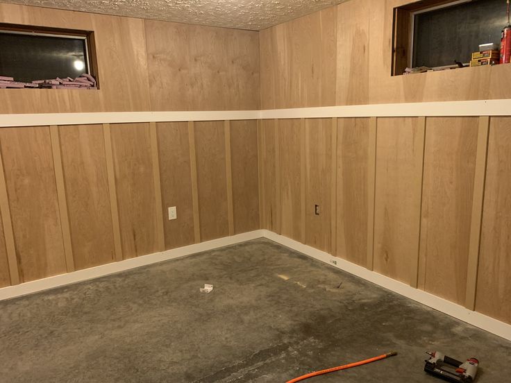 an empty room with wood paneling and tools on the floor