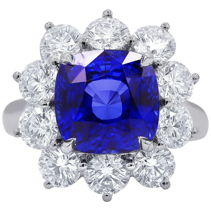 a blue and white ring with diamonds around it on a white background, the center stone is surrounded by three rows of round brilliant cut stones