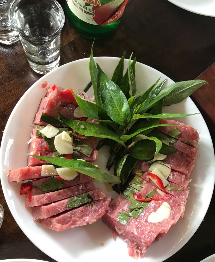 a white plate topped with meat and veggies on top of a wooden table