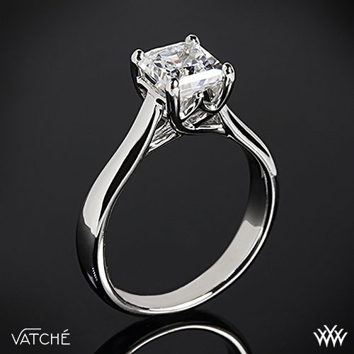 a white gold ring with a princess cut diamond in the center on a black background