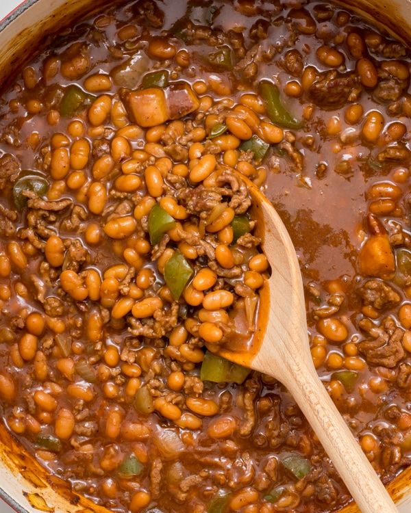 a wooden spoon in a pot filled with beans