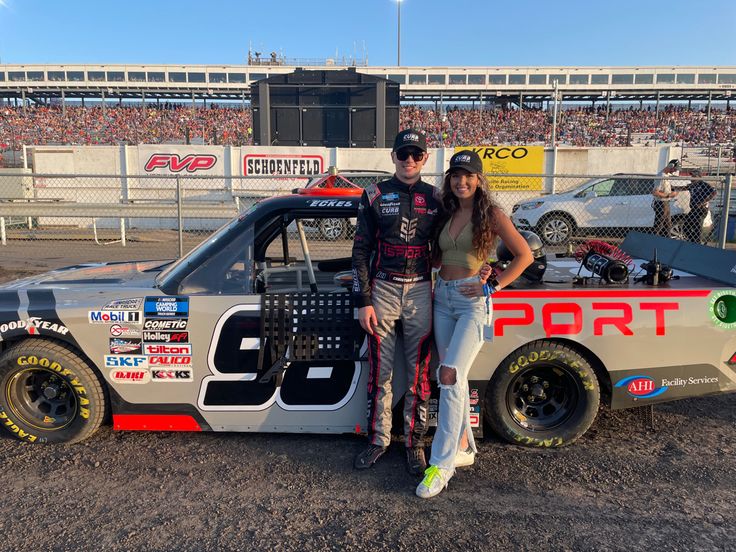 two people standing next to a race car