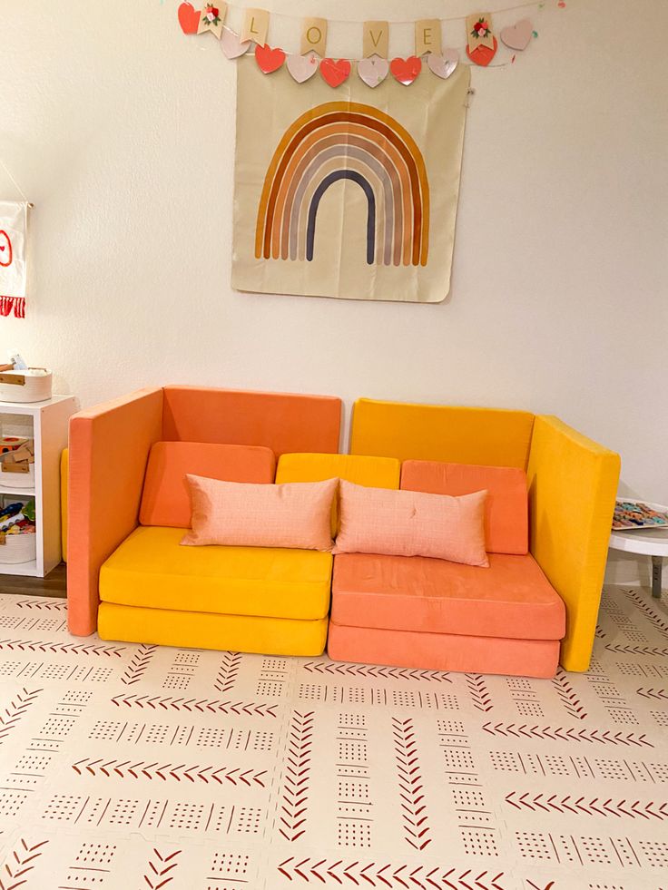 an orange and yellow couch sitting on top of a floor next to a white table