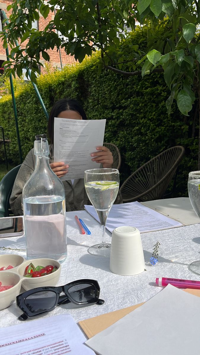 a person sitting at a table with glasses and papers in front of them, reading