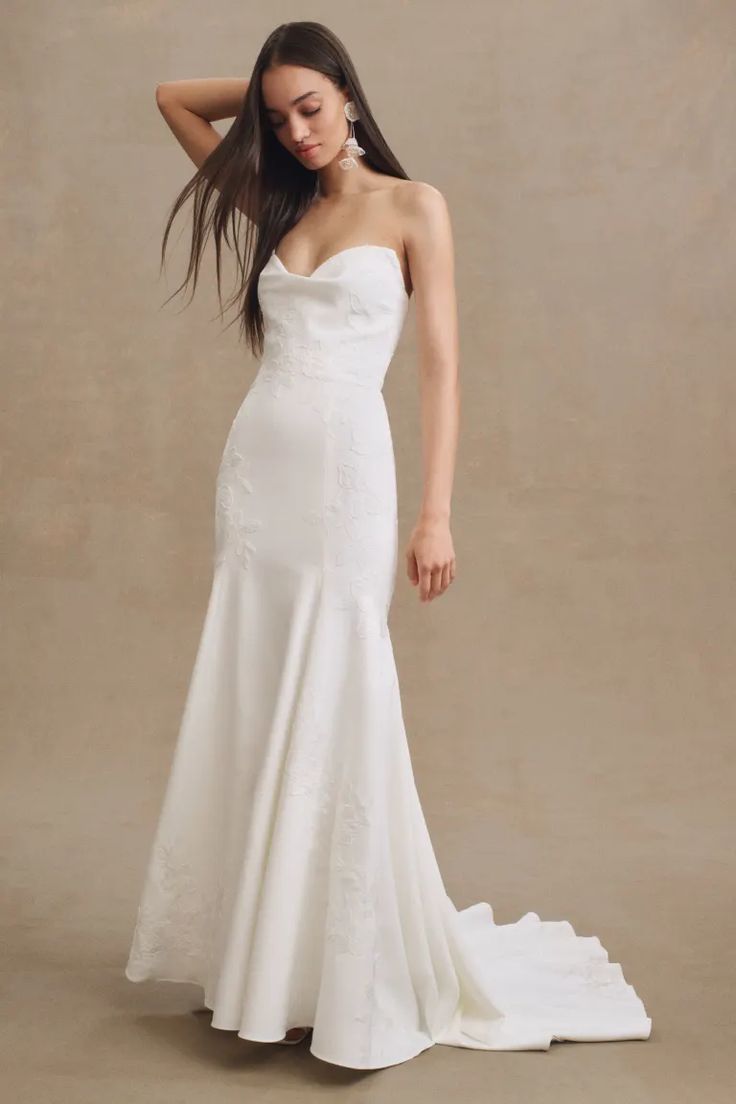 a woman in a white wedding dress posing for the camera with her hand on her head