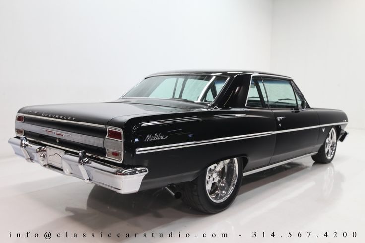 an old black car parked in a white room