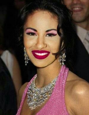 a woman in a pink dress with red lipstick and large jewels on her face is smiling