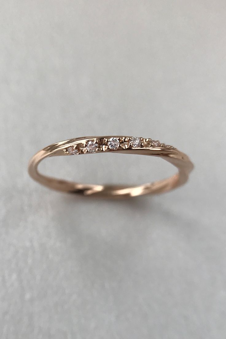 a gold wedding band with five diamonds on the top and bottom, sitting on a white surface