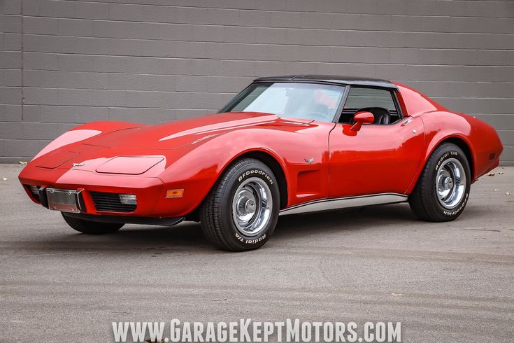 a red chevrolet corvette car parked in front of a garage