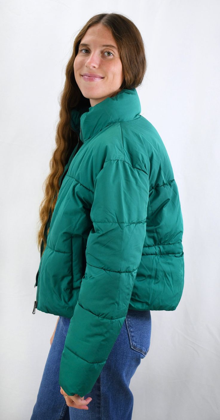 Warm and Fashionable. This cropped puffer jacket adds just the right style to any outfit while keeping you warm. The jacket has a front zipper and pockets to maximize fashion and ease with a back adjustment to cinch the waist for the most flattering fit. Wear this now for those chilly days or on gameday to add just the right color to your outfit. Pairs nicely with Color Fleece Crop. Color- Green (also available in Stone, Blue, Teal, Cheddar Gold, Caramel, Cream, Olive Green, Pale Lavander, Charcoal Blue, Pale Pink, Sky Blue, Hot Pink, Milk Chocolate, Orange, Black, and Lime Green) 80% Polyester 20% Nylon Fall Puffer Quilted Jacket, Green Nylon Puffer Jacket For Fall, Trendy Winter Puffer Jacket With Zipper, Cropped Puffer Jacket For Winter, Cropped Quilted Outerwear For Fall, Green Quilted Puffer Jacket For Fall, Fall Green Quilted Puffer Jacket, Casual Cropped Jacket With Pockets For Cold Weather, Solid Color Spring Puffer Quilted Jacket