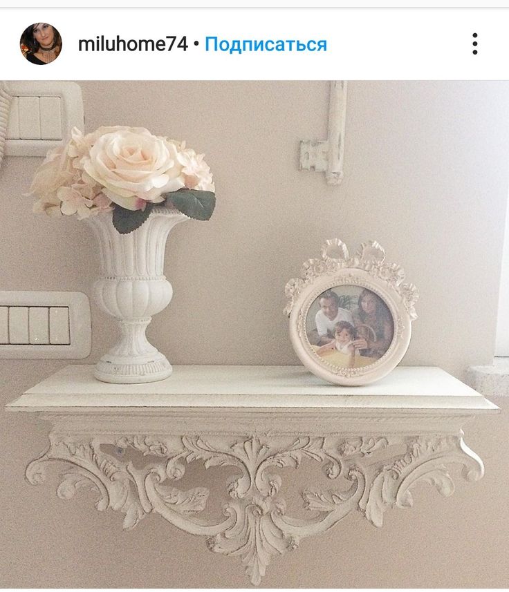 there is a white vase with flowers on top of a shelf next to a mirror