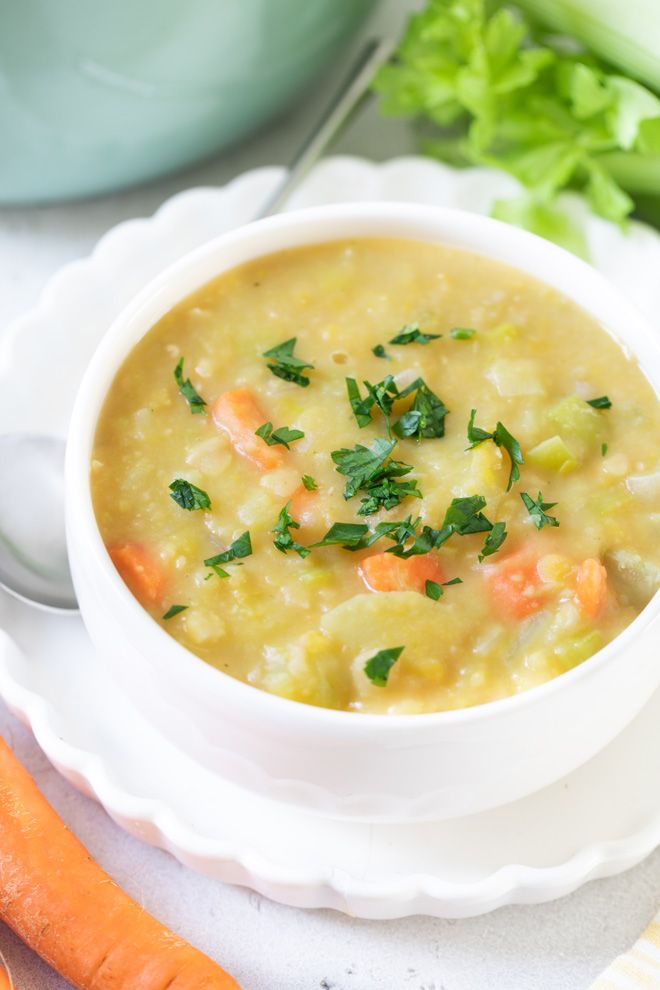 a bowl of soup with carrots, celery and parsley