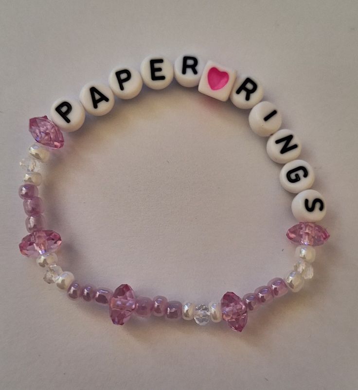 a beaded bracelet with pink and white beads that spell out paper rivets