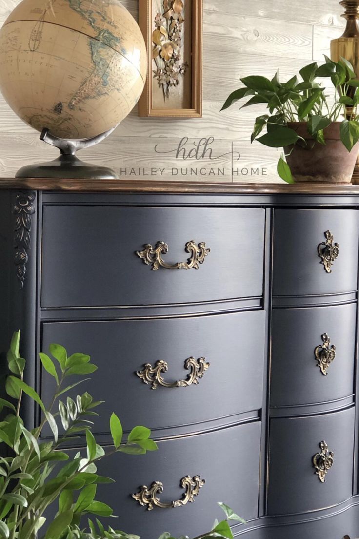 an old dresser has been painted blue with gold hardware and is next to a potted plant