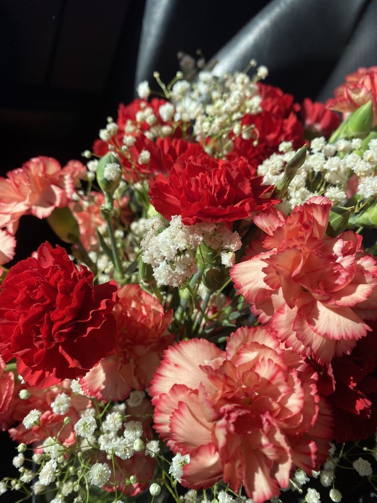 a bouquet of red and white flowers sitting on top of a black cloth covered seat