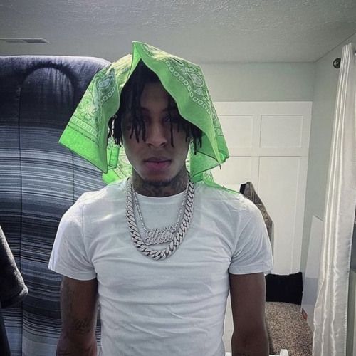 a young man wearing a green bandana on top of his head