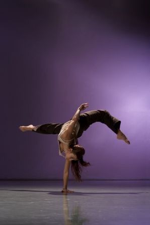 a woman doing a handstand on the floor in front of a purple background