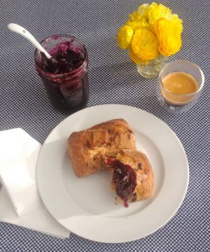 a white plate topped with a piece of cake next to a cup of tea and flowers