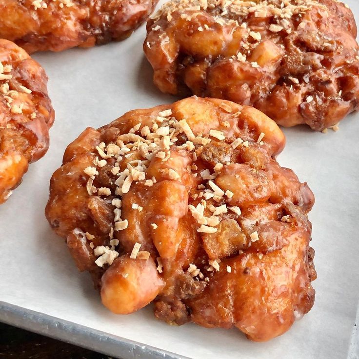 several doughnuts with nuts are on a baking sheet