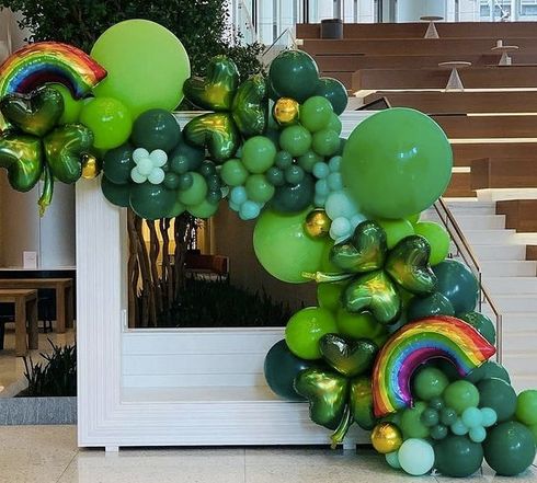 the balloon arch is decorated with shamrocks, balloons and rainbows for st patrick's day