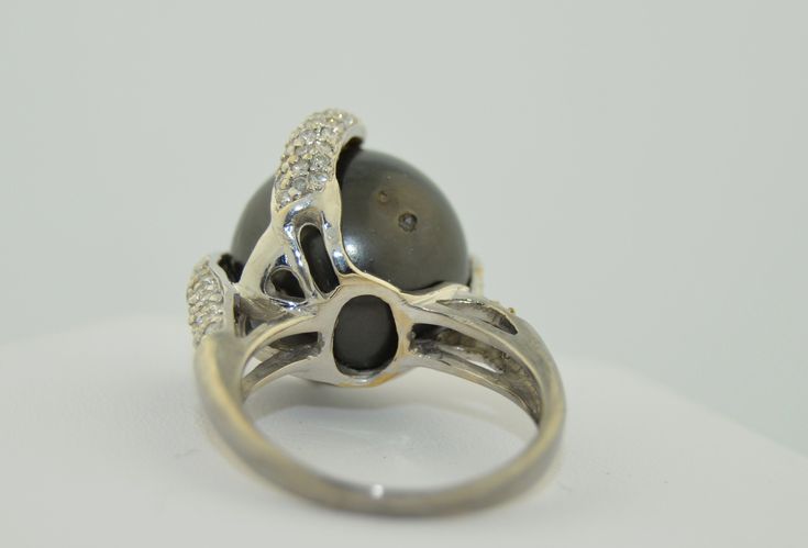 This is an impressively large pearl ring. The pearl is a south Sea Black Tahitian Pearl. The pearl is drilled and mounted with pave diamond accents. The small prong is drilled on the side and the fingers of diamonds are securing the pearl with no movement. This pearl is big, measuring in at 15.5 mm. It is a deep grey/black, perfectly round. There are a couple of natural dimples on the side not the top of the pearl as photographed The setting is 14K White gold, not hallmarked but tested and guara Fine Jewelry With Tahitian Pearl And Diamond Accents, Tahitian Pearl Jewelry With Diamond Accents For Wedding, Tahitian Pearl Ring With Diamond Accents For Wedding, Tahitian Pearl Ring With Diamond Accents Fine Jewelry, Classic Tahitian Pearl Ring With Diamond Accents, Fine Jewelry Tahitian Pearl Ring With Diamond Accents, Tahitian Pearl Ring With Diamond Accents, Luxury Tahitian Pearl Ring With Diamond Accents, Tahitian Pearl Rings With Diamond Accents For Anniversary