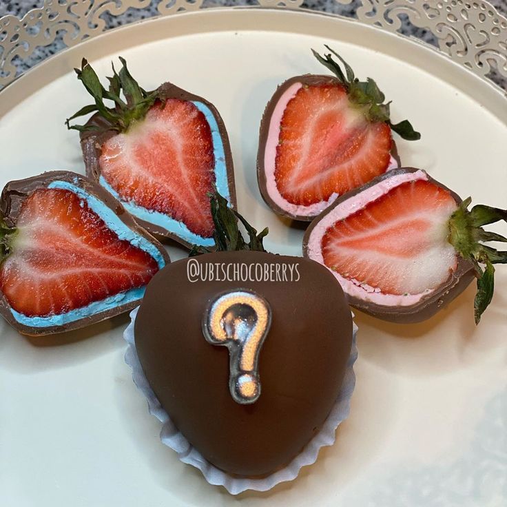 four chocolate covered strawberries on a plate with a question mark painted on the top