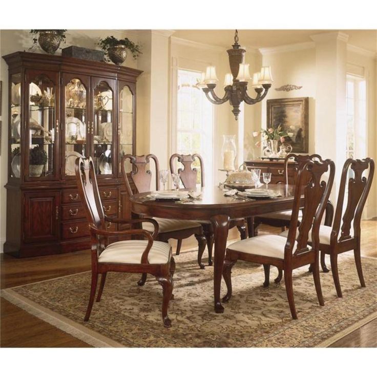 a dinning room table with chairs and a china cabinet in the corner next to it