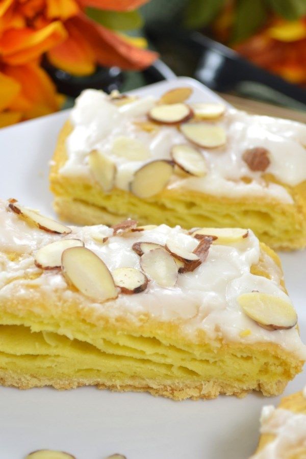 three pieces of cake on a plate with flowers in the background