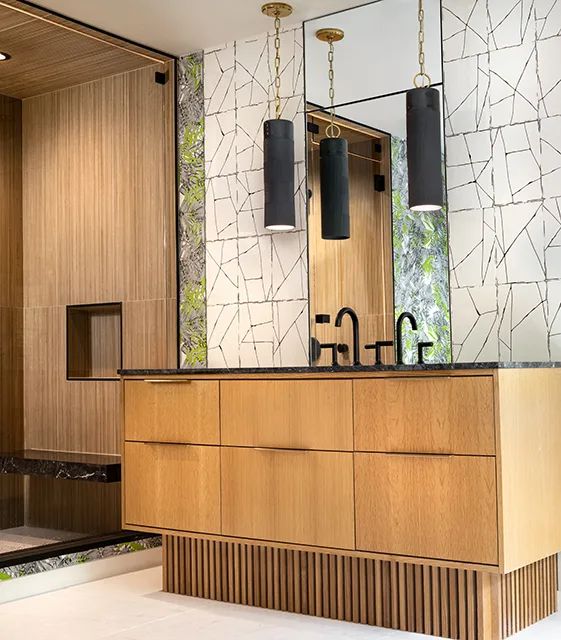 a modern bathroom with wooden cabinets and marble counter tops, along with black pendant lights