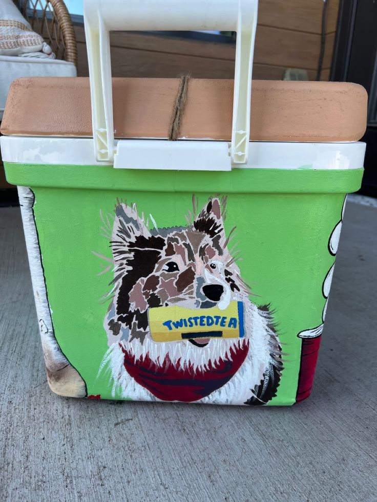 a green and white cooler with a dog painted on it's side, sitting on the ground