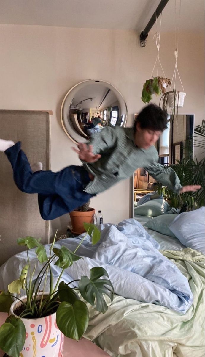 two people jumping in the air over a bed