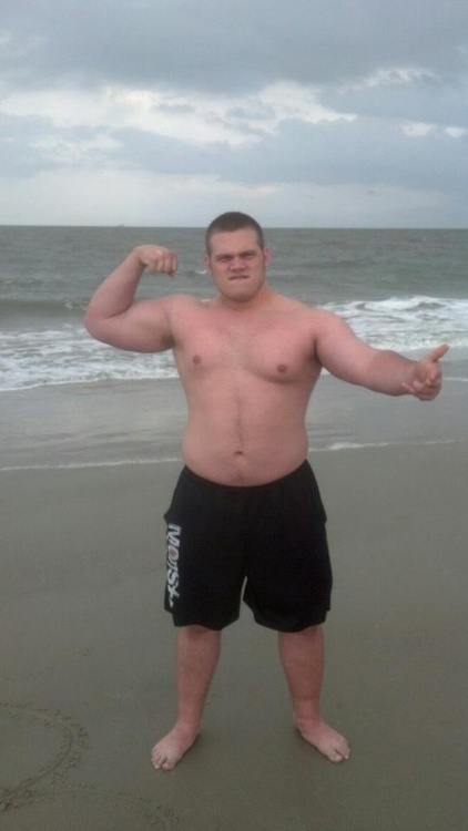 a man standing on top of a beach next to the ocean with his arms in the air