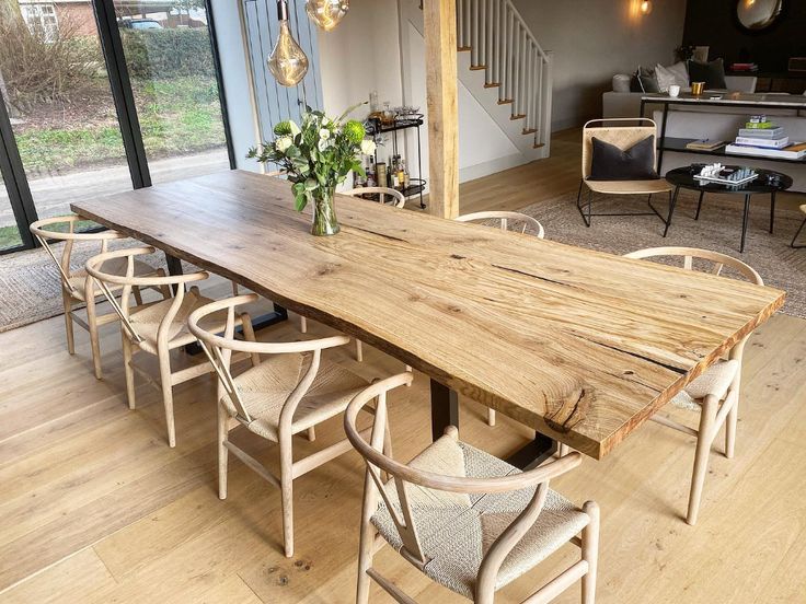 a large wooden table sitting in the middle of a living room with chairs around it