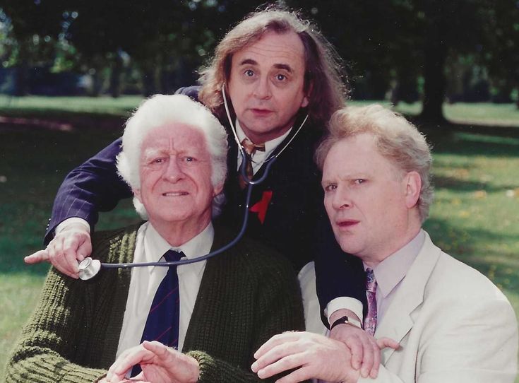 two men and an older man are posing for a photo in front of some trees