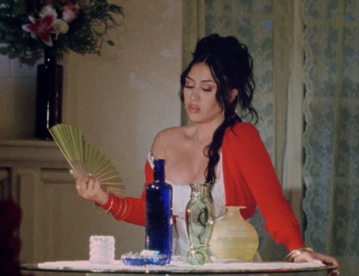 a woman sitting at a table holding a fan