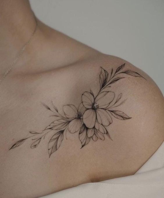 a woman's chest with flowers and leaves tattooed on her left side breast piece