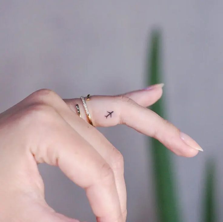 a woman's hand with a tiny bird tattoo on her left thumb and finger