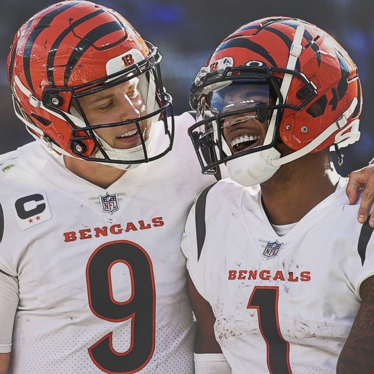 two football players standing next to each other with helmets on and one has his mouth open