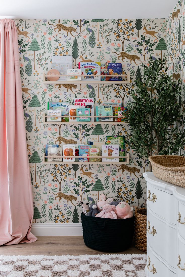 a room with wallpaper and pink drapes in the corner, next to a basket full of toys