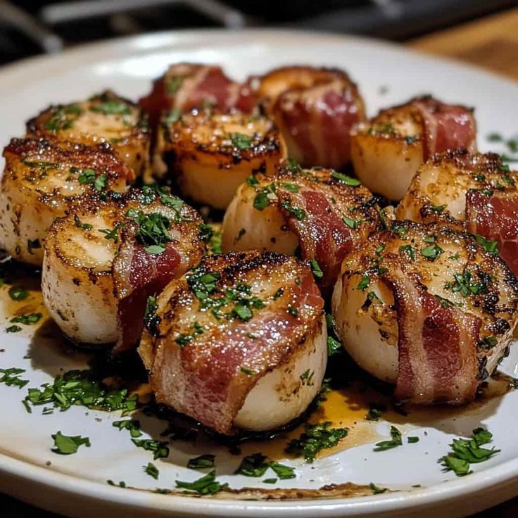 there are some bacon wrapped scallops on the plate and garnished with parsley