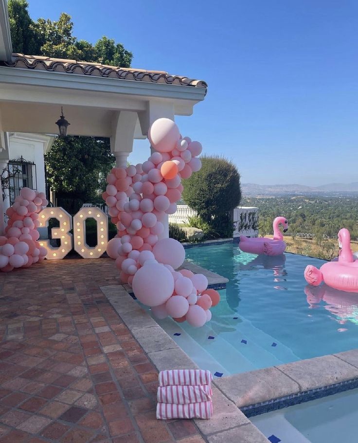 balloons are floating in the air next to a swimming pool with flamingos on it